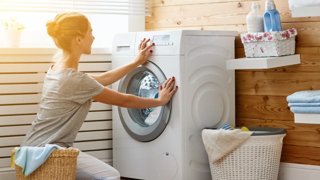 A woman turns the dial on a washing machine