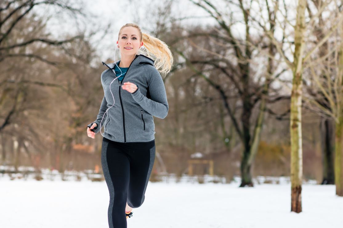 woman running through woods with snow