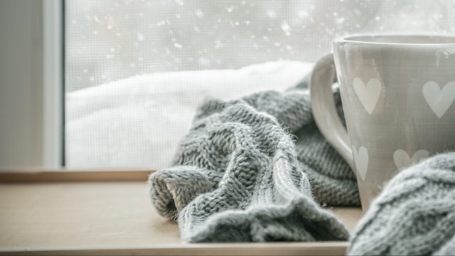 mug and a blanket in front of snowy window