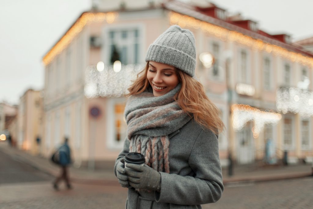 Women with a hot drink and winter clothes on. Hat, scarf and gloves.